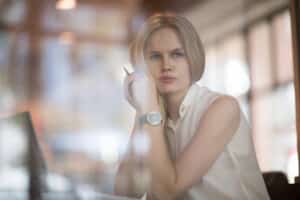 Woman sitting at her work desk, unhappy after experiencing workplace harassment.