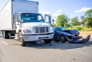 Small blue sedan crushed after a commercial vehicle accident involving a white delivery truck